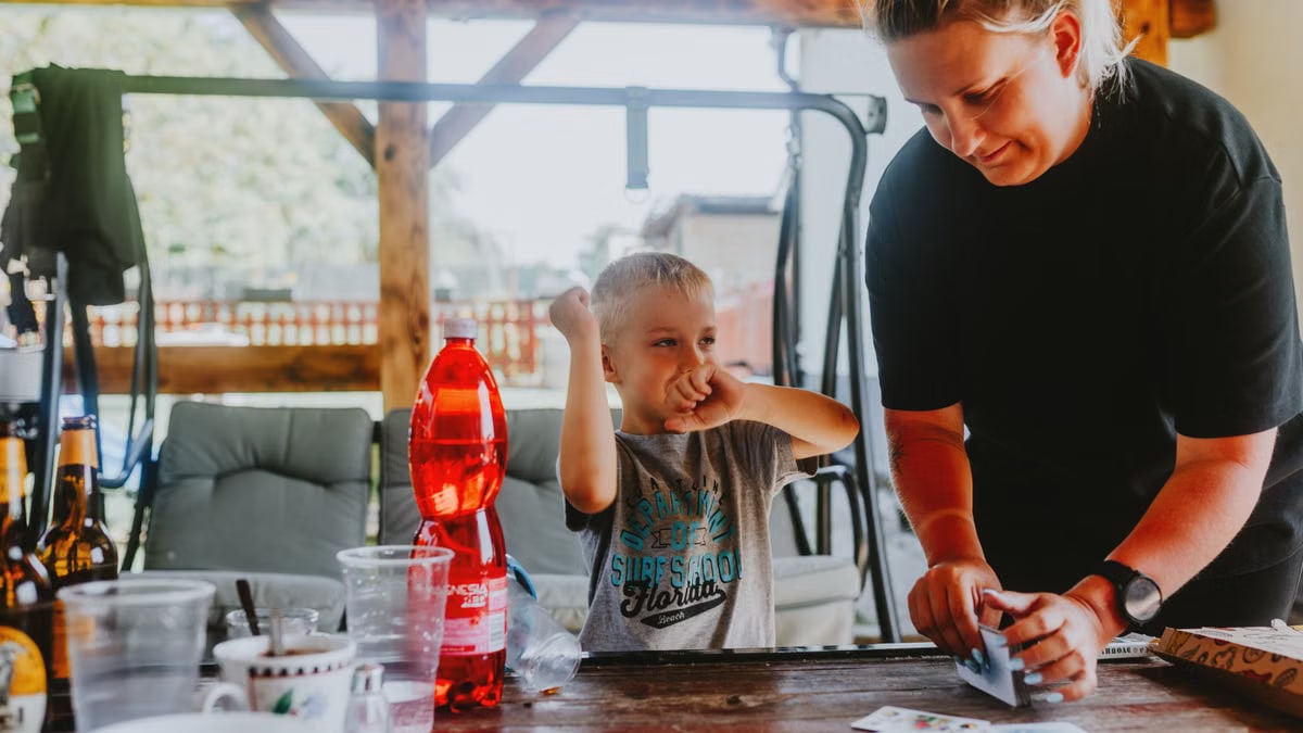A cheerful moment of a mother and child playing cards outdoors in a backyard.